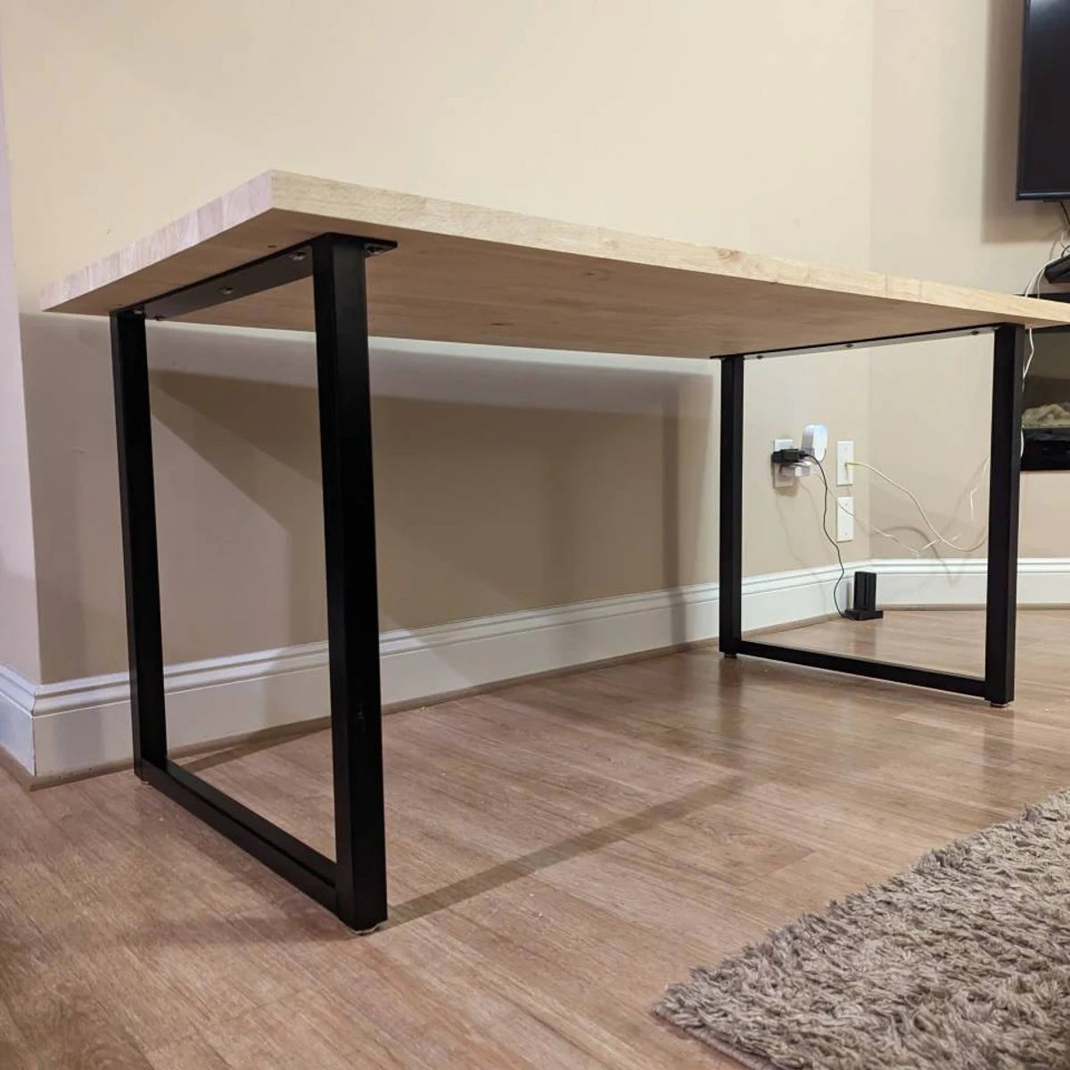 Wooden desk with black metal legs in a room setting.