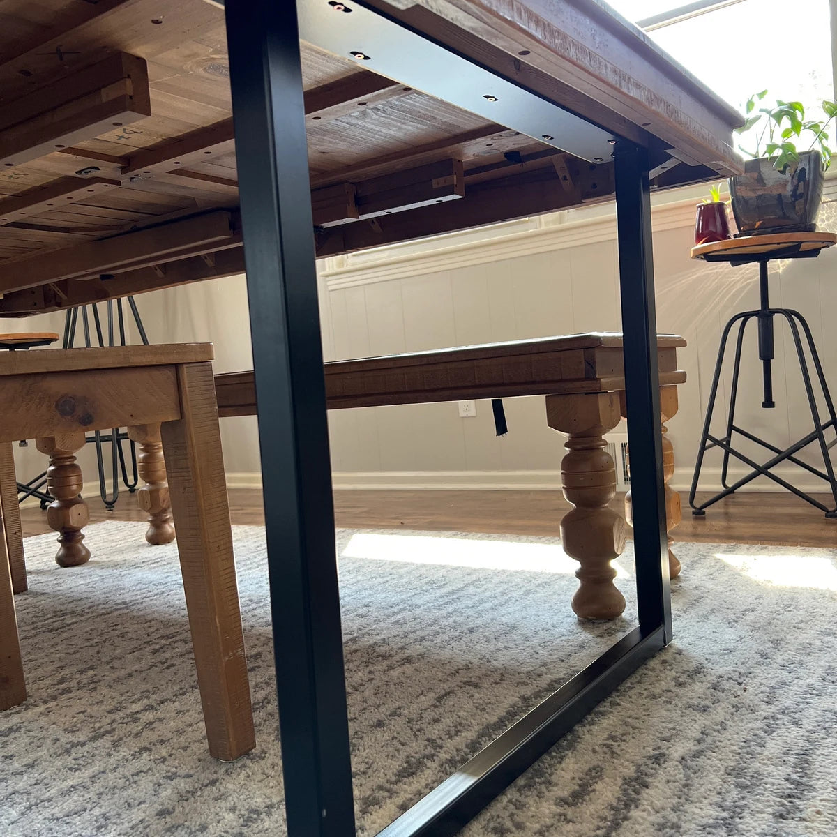 Wooden dining table with metal legs in a room with a carpeted floor.