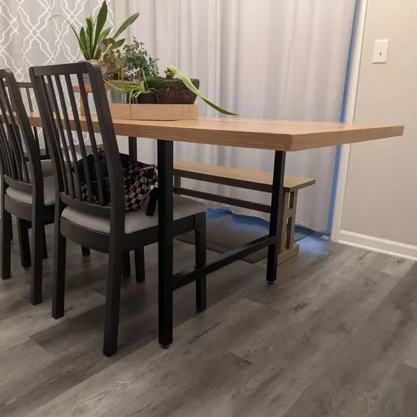 Dining table with chairs in a room with gray flooring and white walls.